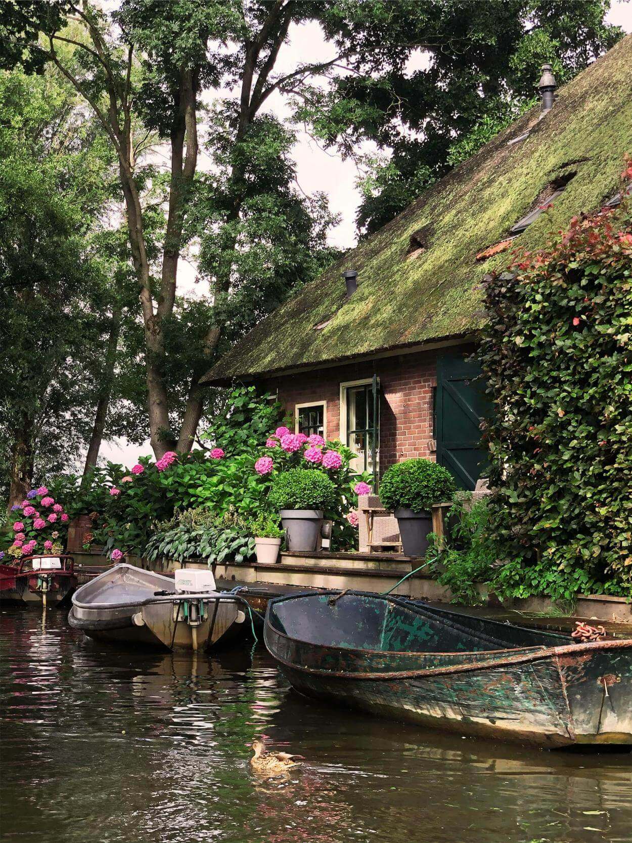 2 small boats at a typical Giethoorn house with a thatched roof